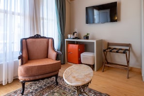 Una sala de estar con un sillón antiguo, una mesita redonda, un aparador y un banco.
