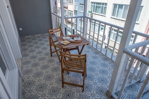 Varanda com piso estampado, mesa de madeira com cadeiras e guarda-corpo.