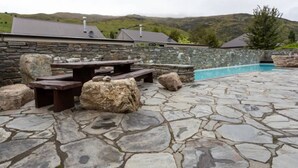 A stone patio with picnic tables and a swimming pool. - Studio 26 - One Bedroom Place with Pool (Cardrona)
