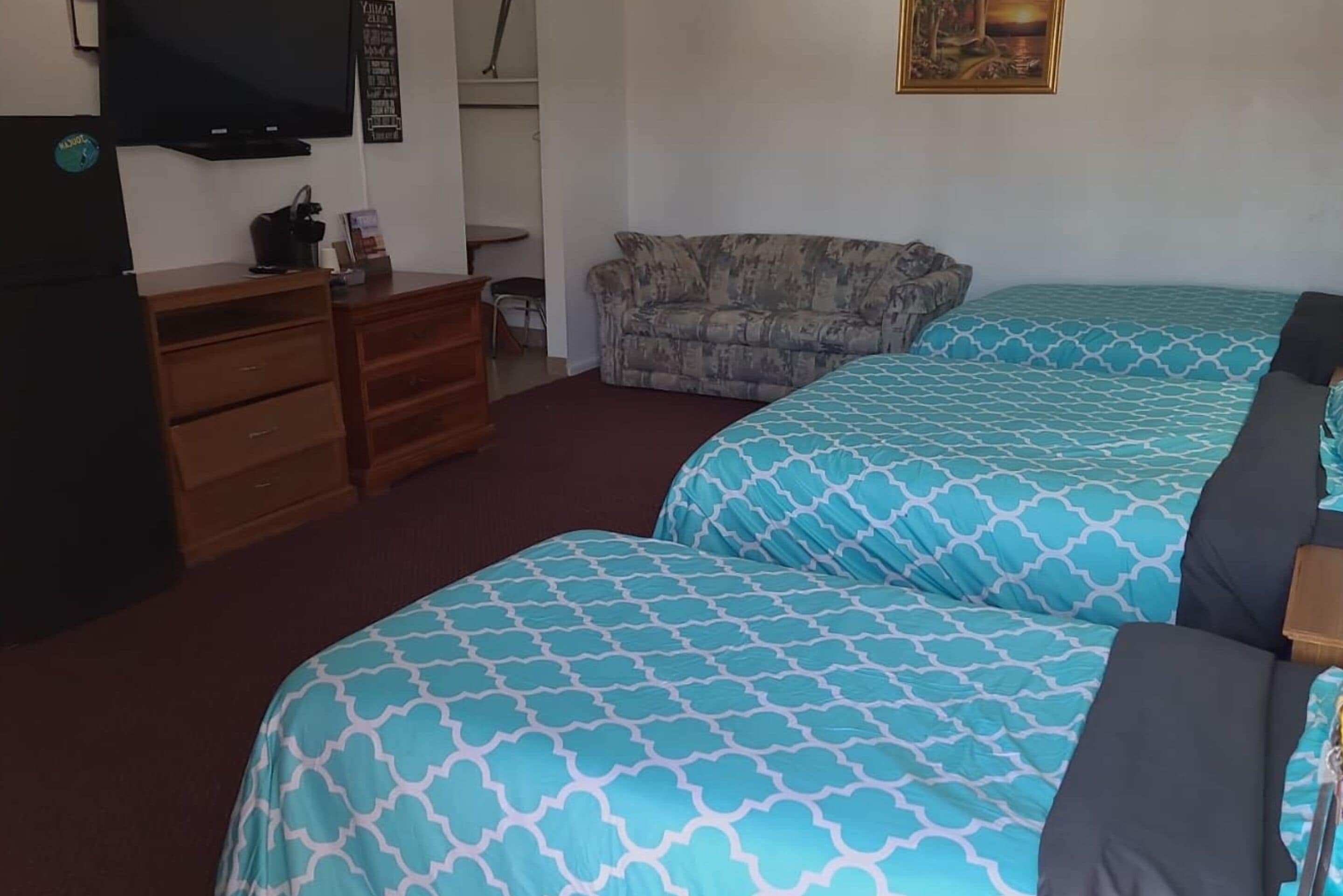 Ein Schlafzimmer mit zwei Betten, einer Holzkommode, einem Fernseher und einem Sofa.
