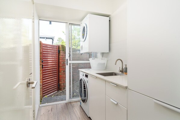 A compact laundry room with a washing machine, a sink, and a cabinet.