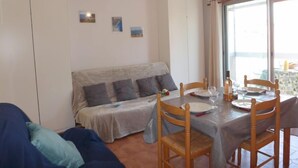 A cozy room with a bed, a dining table set for two, and a large window offering a view. - L'Espelido by Interhome (Saint Aygulf)