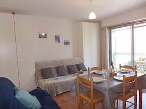 Een gezellige kamer met een bed, een eettafel gedekt voor twee personen en een groot raam met uitzicht.