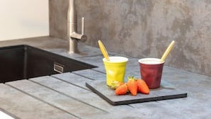 A kitchen counter with a sink, two cups with straws, and a few strawberries. - Hemisphère by Interhome (Carnac)