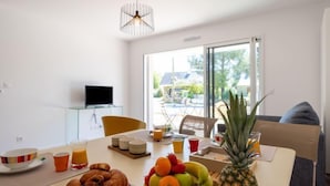 A modern dining area with a table set for breakfast, including croissants, fruits, and juice. - Hemisphère by Interhome (Carnac)