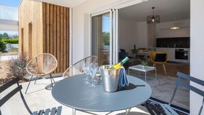 A modern outdoor dining area with a round table, metal chairs, and a bottle of champagne. - Hemisphère by Interhome (Carnac)