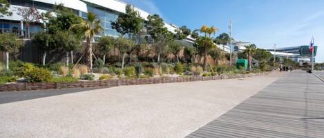 A modern building with a flat roof and large glass windows, surrounded by a landscaped area with various plants and trees.