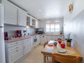 Een koelkast, een oven, een vaatwasser, kookgerei, borden en bestek