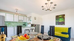 A modern kitchen with white cabinets, a green backsplash, and a dining area with a table set for two. - La Storia by Interhome (Cogolin)
