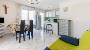A compact living space with a dining area, kitchenette, and a sofa with cushions. - La Storia by Interhome (Cogolin)