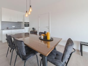 A modern kitchen with white cabinets, a microwave, and a hanging light fixture.