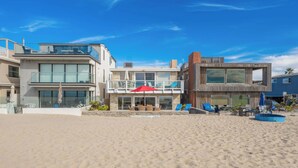 Een strandpand met moderne architectuur, inclusief een glazen balkon en een houten terras.