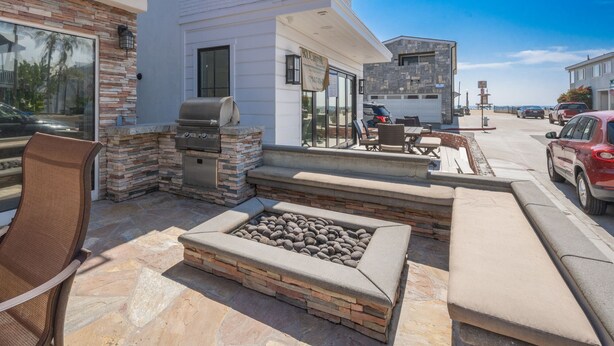 Un patio exterior con una chimenea de piedra, asientos y una parrilla.