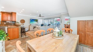 Una cocina amplia con comedor, una sala de estar con un ventanal grande y un ventilador de techo.