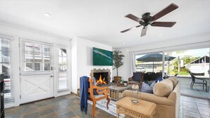 A spacious living area with a fireplace, comfortable seating, and a view of the outdoors. - Spacious 3 Bedroom Home w/ Fire Pit at the Beach! (Newport Beach)