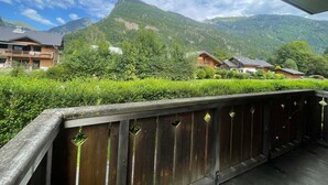 A wooden balcony with a view of a mountain and several buildings. - Quiet apartment in Samoëns with pool and WiFi (Samoëns)