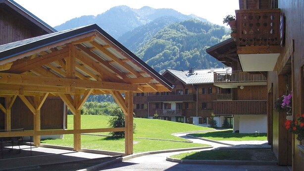 A wooden building with a covered patio area and a view of a mountain. - Quiet apartment in Samoëns with pool and WiFi (Samoëns)