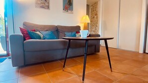 Ein Wohnzimmer mit einer Couch, einem kleinen Tisch, einer Lampe und einem Poster an der Wand.