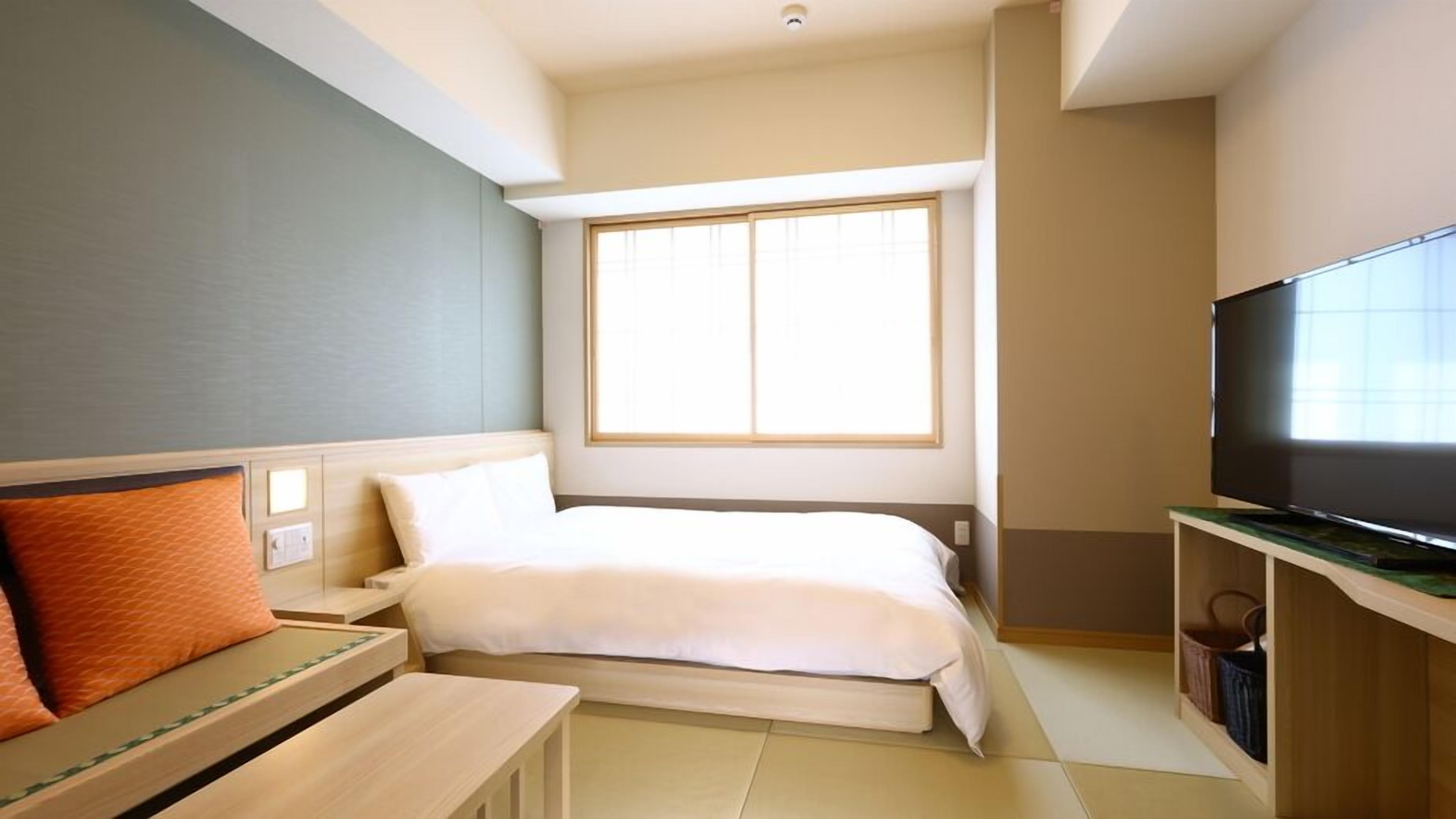 Una habitación de hotel con cama, televisión, escritorio y ventana.