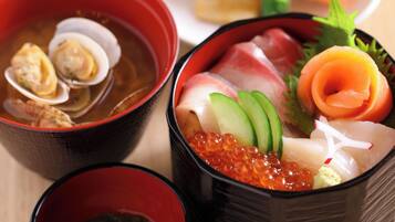 En traditionell japansk måltid med sashimi, lax och rom, serverad i svarta skålar.