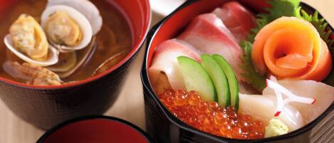 Een traditionele Japanse maaltijd met sashimi, zalm en roe, geserveerd in zwarte kommen.