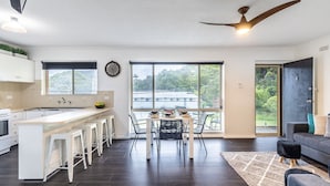A modern kitchen with a bar area, large windows, and a ceiling fan.