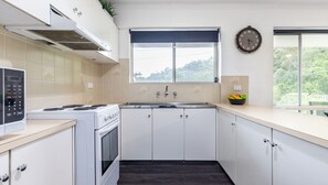 Una cocina moderna con armarios blancos, una estufa y un ventanal con vistas a zonas verdes.