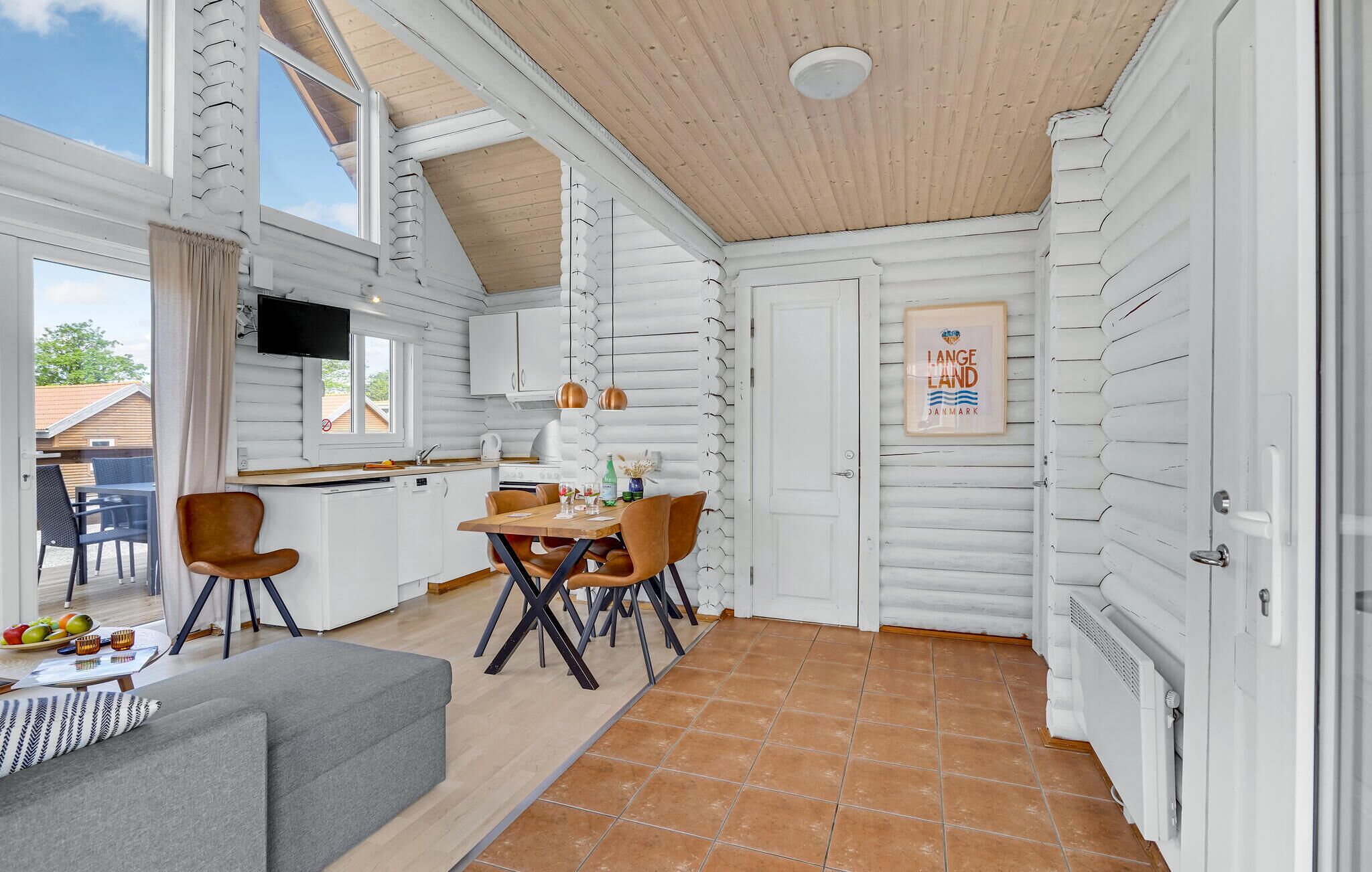 A compact kitchen with a dining area, wooden ceiling, and a view of the outdoors.