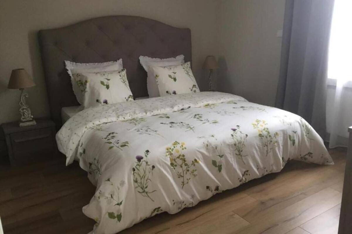 A bedroom with a large bed, two bedside tables, and a nightstand.