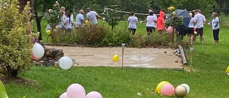 Un grup de persones en un jardí amb un camí de terra, envoltat de verdura i globus.