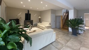 Amplia sala de estar con un sofá blanco, una chimenea y una escalera que conduce a otro nivel.