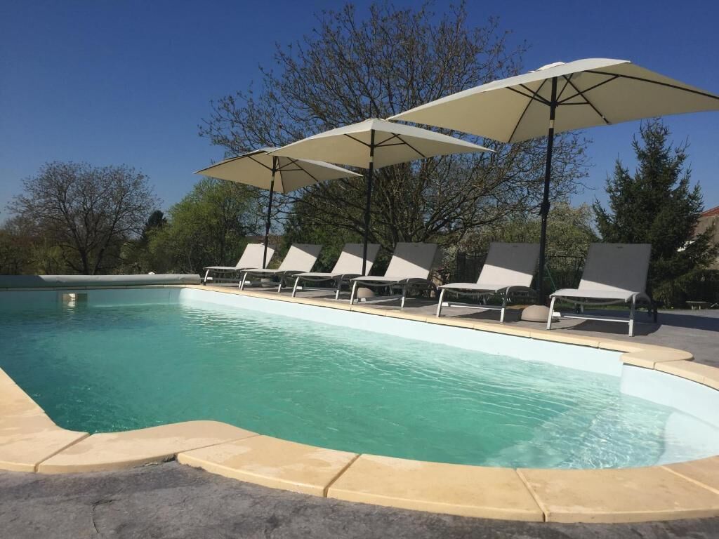 En swimmingpool med liggestole og parasoller.