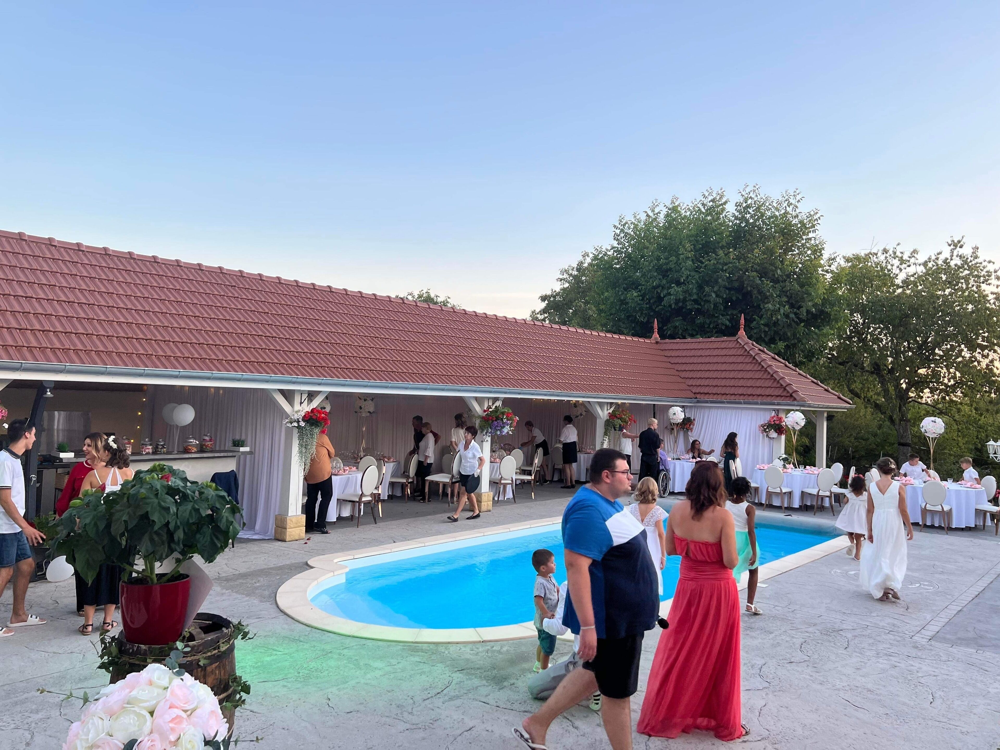 Un événement organisé au bord de la piscine, avec un espace couvert et des tables disposées pour accueillir les invités.