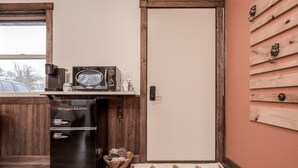 Une cuisine compacte avec un réfrigérateur noir, un four à micro-ondes et une machine à café, le tout posé sur un plan de travail en bois.