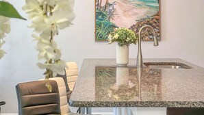 A kitchen with a granite countertop, a stainless steel sink, and a vase with flowers. - Storey Lake Home w/ Pool | Mins to Disney | 4BR | Waterpark (Kissimmee)