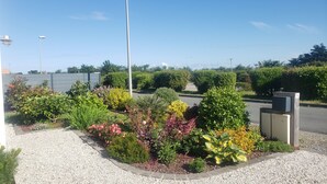 En anlagt have med forskelligt løv og blomster, en grussti og et hegn i baggrunden.