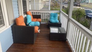 A wooden deck with wicker furniture and cushions, a glass table, and a white railing. - Cozy, 2 BR APt in Worcester Close to Downtown, Palladium, DCU center, Polar Park (Worcester)