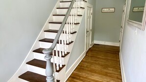 A staircase with white balusters and dark wood steps leading to a door with a 'Welcome' sign. - Cozy, 2 BR APt in Worcester Close to Downtown, Palladium, DCU center, Polar Park (Worcester)