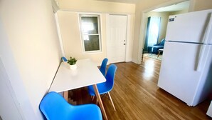 A small kitchen with a white refrigerator, a dining table with blue chairs, and a potted plant on the table. - Cozy, 2 BR APt in Worcester Close to Downtown, Palladium, DCU center, Polar Park (Worcester)