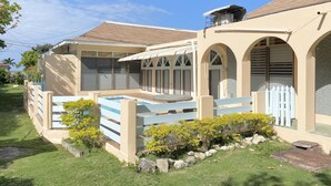 Una casa con piscina, patio cercado y jardín con flores amarillas.