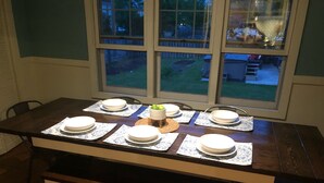 A dining table set with plates, a bowl, and a small vase. - The Brickmason’s House (Racine)
