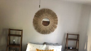 A bedroom with a bed, two wooden shelves, a wall-mounted mirror, and a hanging light fixture. - The Brickmason’s House (Racine)