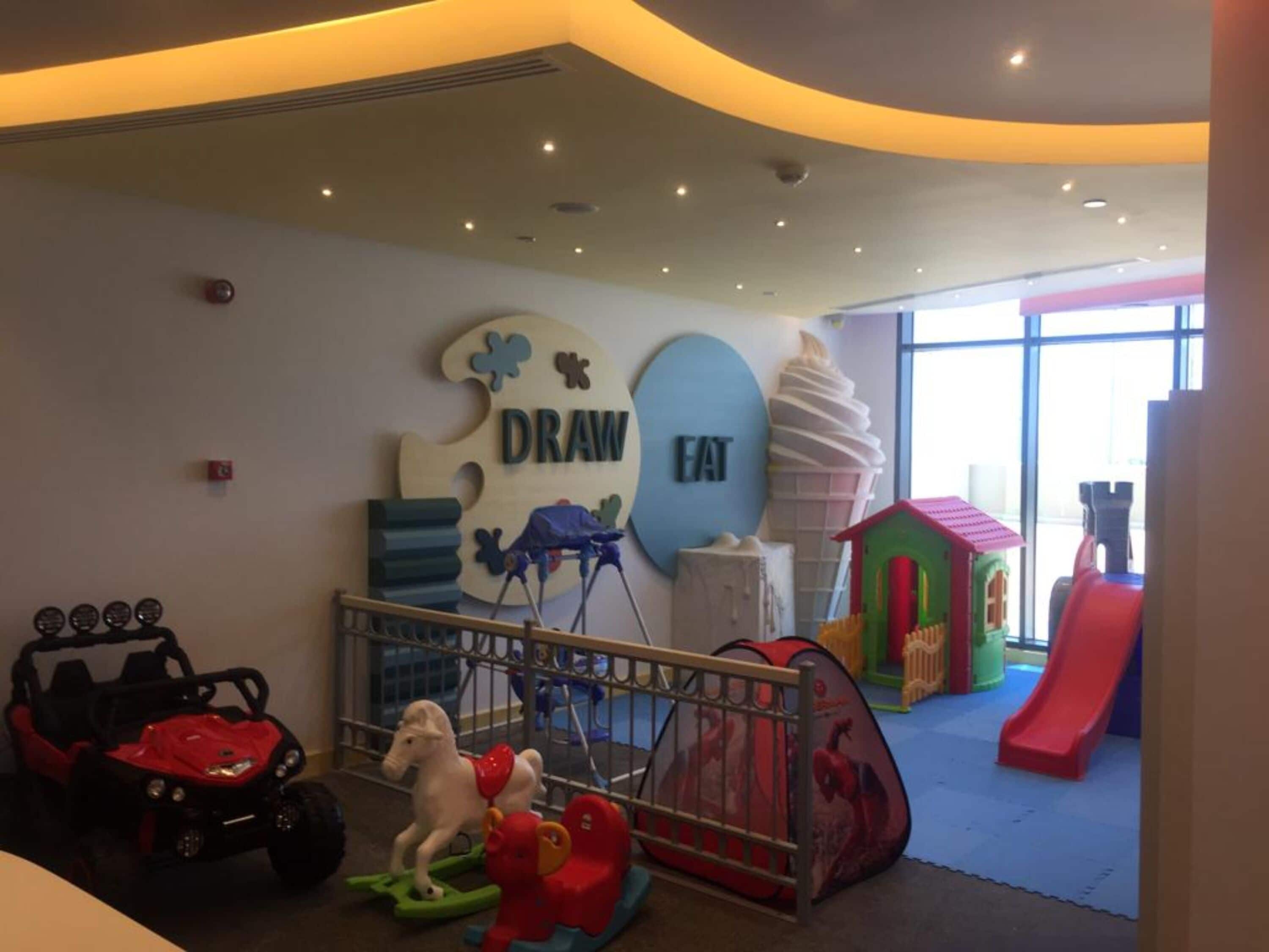 A children's play area with a slide, a playpen, and a toy car.