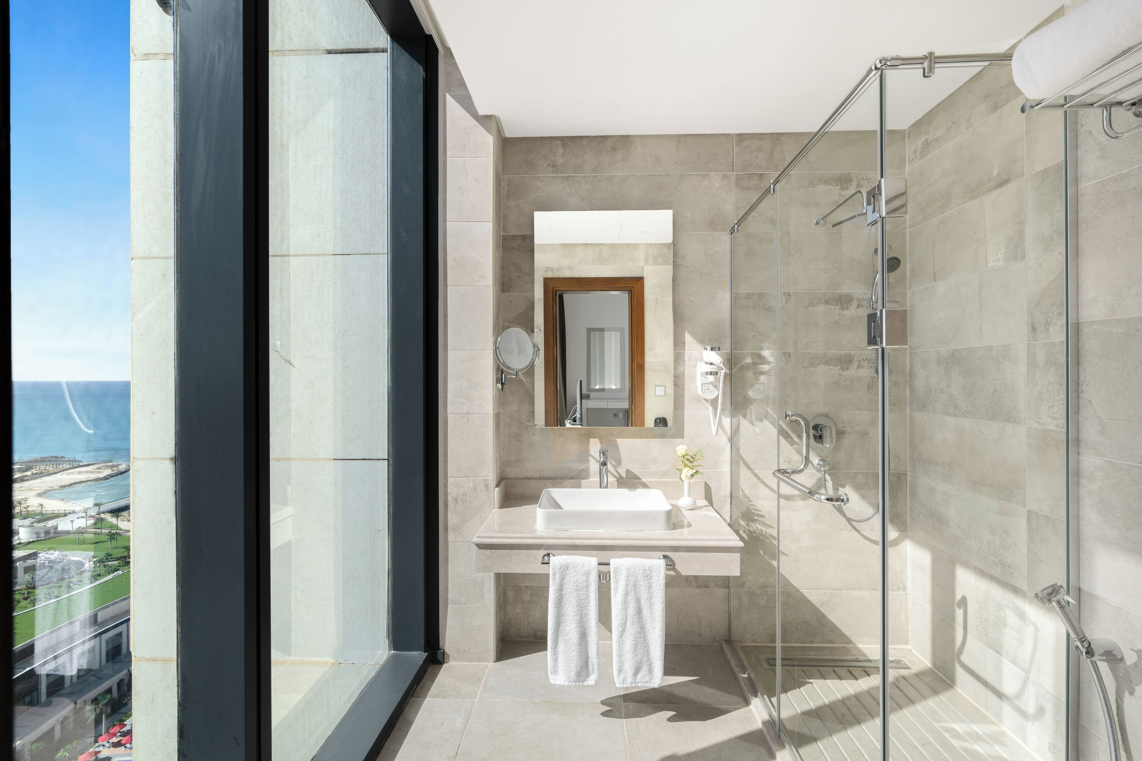 A modern bathroom with a glass shower, a sink, and a mirror.