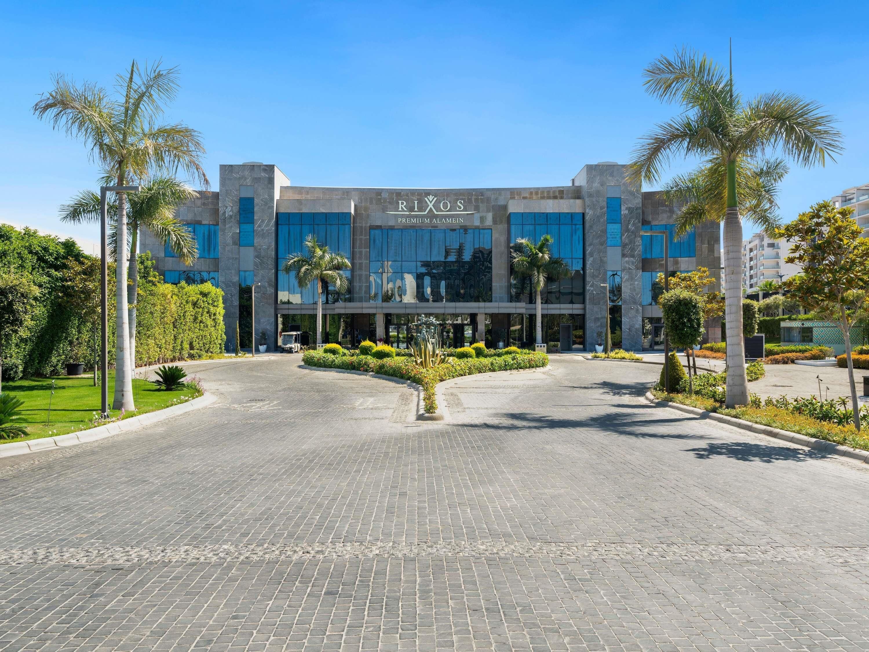 Un bâtiment moderne doté d’une façade en verre, sur lequel on peut lire l’inscription « RIXOS PREMIUM ALAMAIN ».