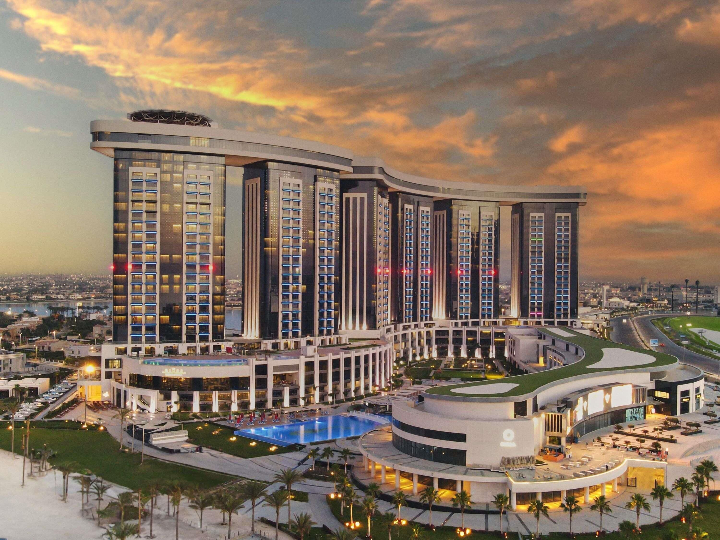 Um hotel moderno com vários edifícios altos, piscina e área ajardinada.