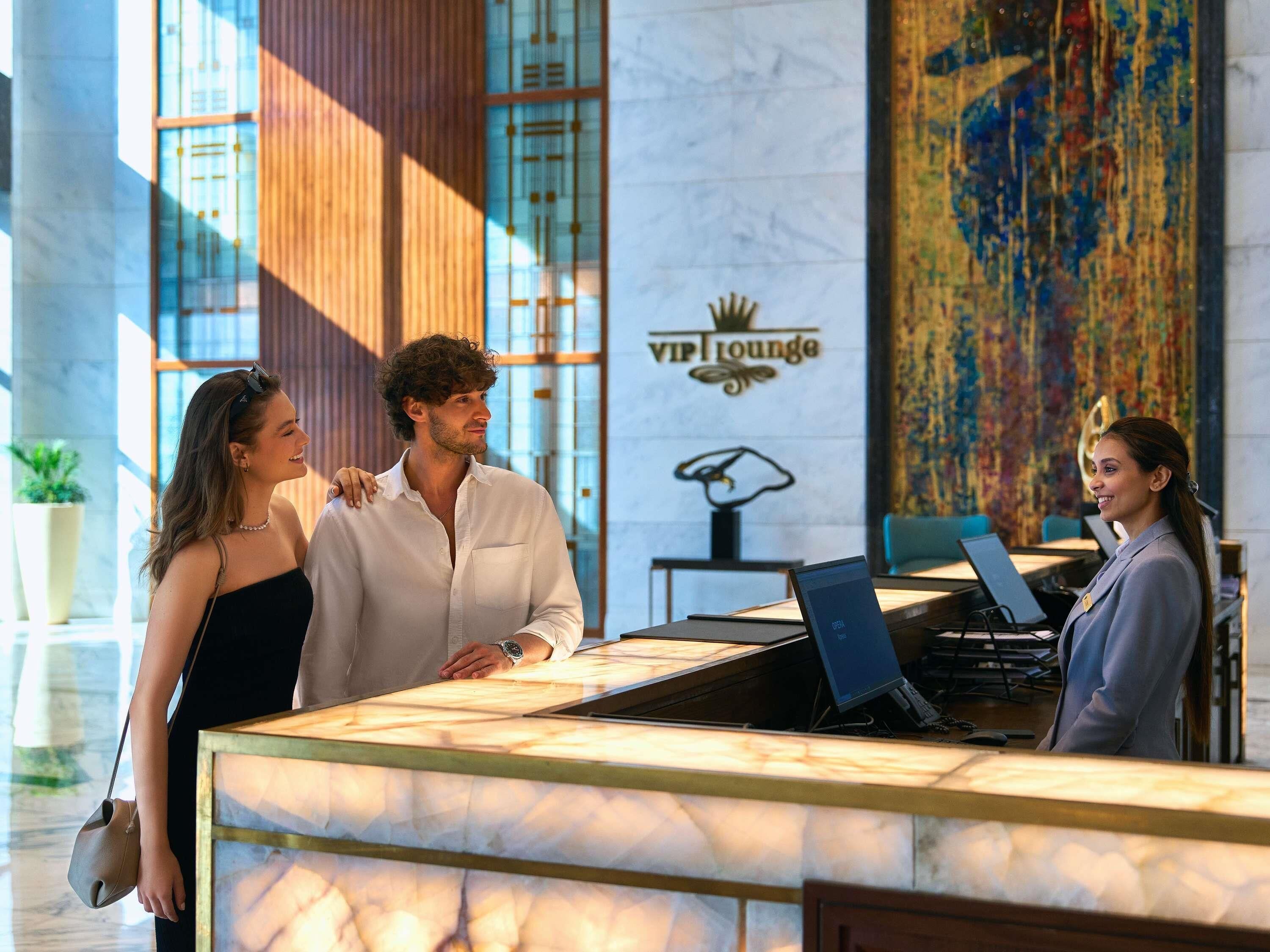 A reception desk with a marble top, a logo for 'VIP Lounge,' and a large abstract painting on the wall.