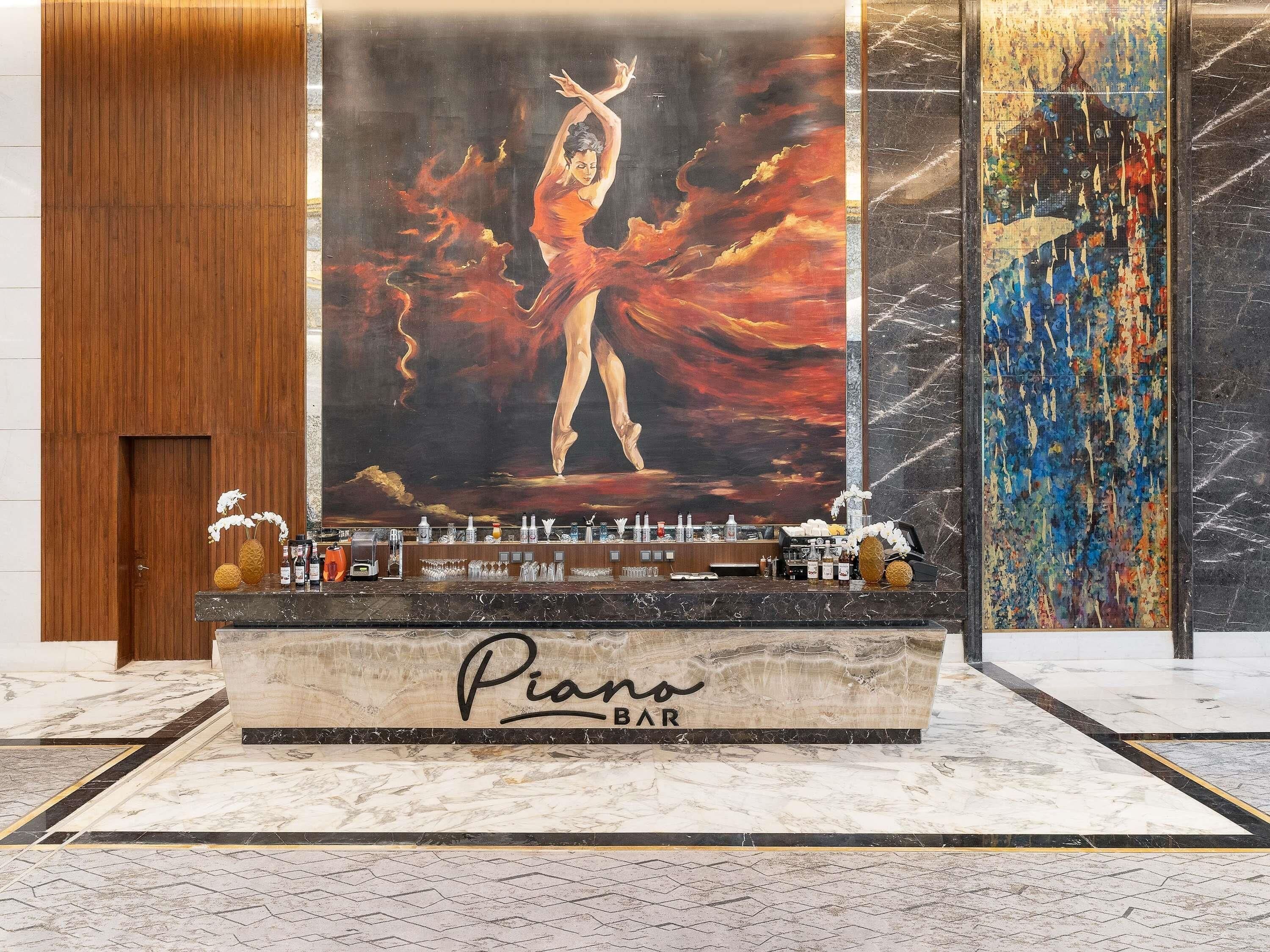 Een bar met een pianobar bord, een groot abstract schilderij en een toog met verschillende flessen en glazen.