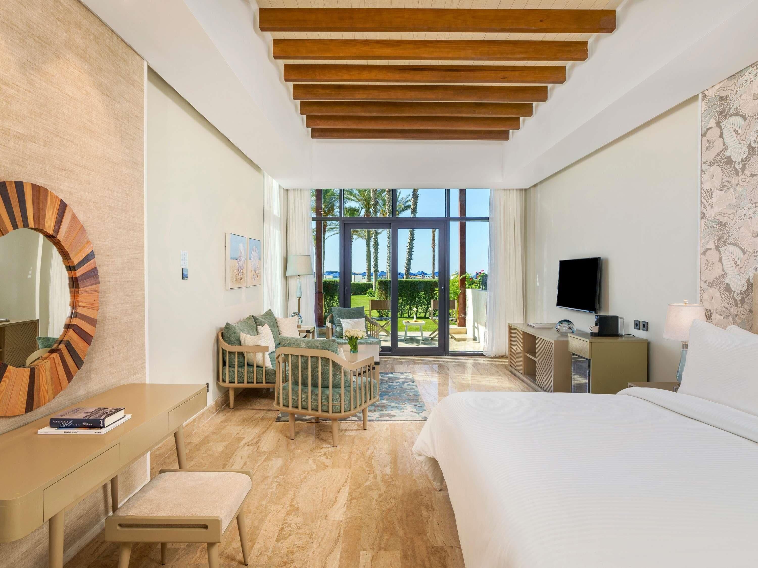 Een moderne hotelkamer met een bed, bureau, stoel en uitzicht op het landschap.