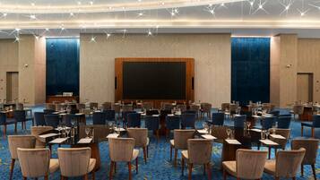 A conference room with multiple tables and chairs, a large screen, and star-shaped ceiling lights.